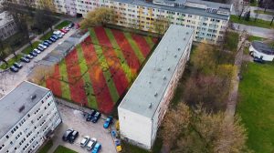 Na zdjęciu widok z góry na kilka bloków mieszkalnych i boisko